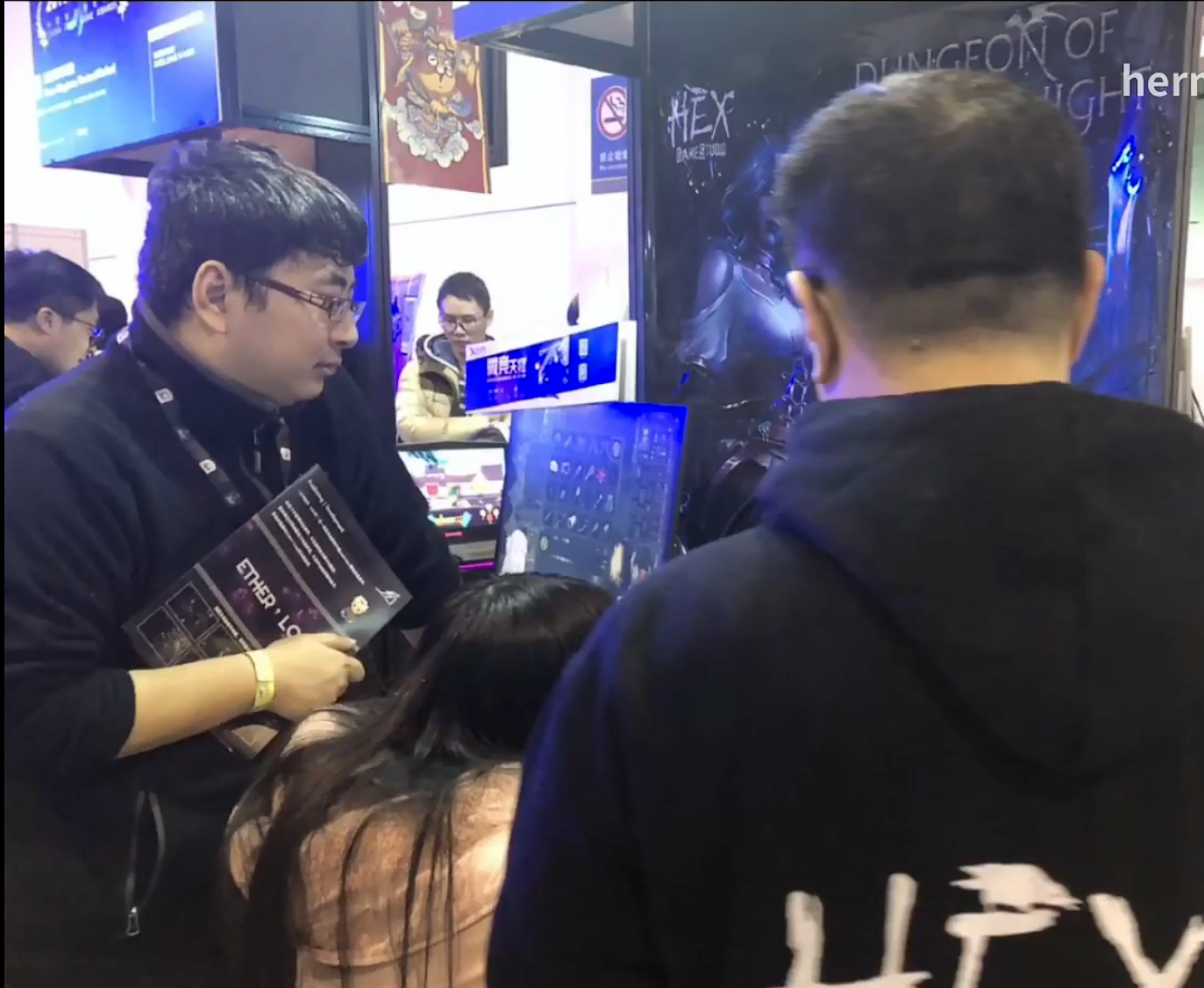 Visitors trying games at exhibition booths, with people blurred